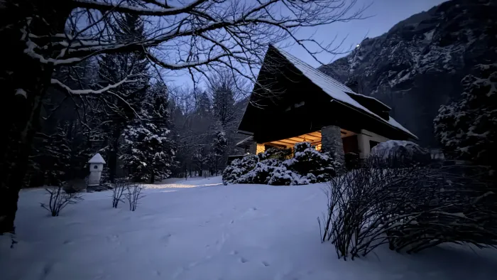 A snowman in the garden at Red Beech Cabin, cabin lit up at dusk